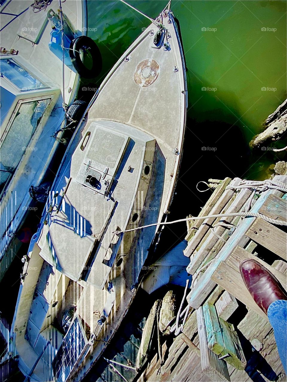 Two boats, tied to the wall at Newtown Creek in LIC are seen from the land at low tide. To the left, “Salvation” & on the right is someone else’s boat serving primarily for storage. We pass over it to get to our boat. 2022. Hypnotic Productions