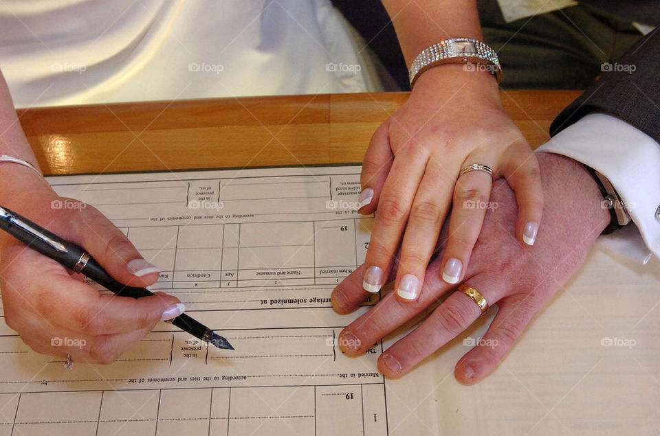 Close up of bride and groom signing the register.