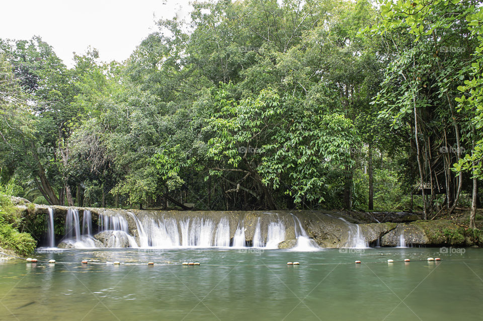 The water flowing over rocks and trees down a waterfall at Kapao waterfall National Park ,Chumphon in Thailand.