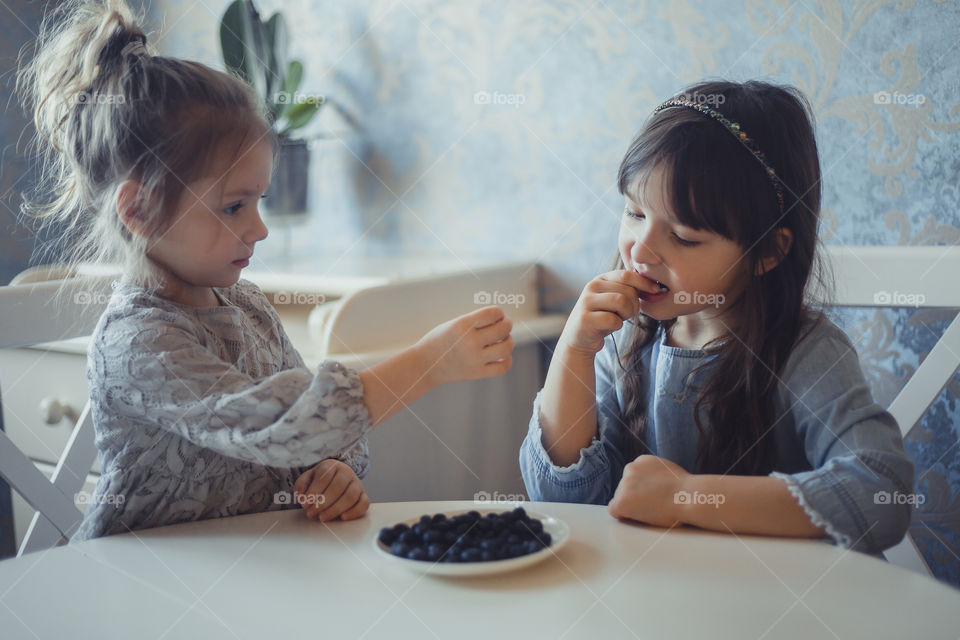 Little sisters with blueberries at home 