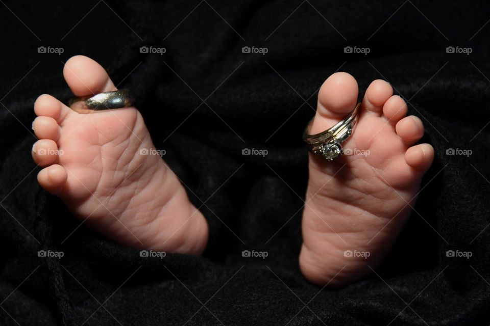 Father’s wedding ring and mother’s wedding ring on their newborn’s toes