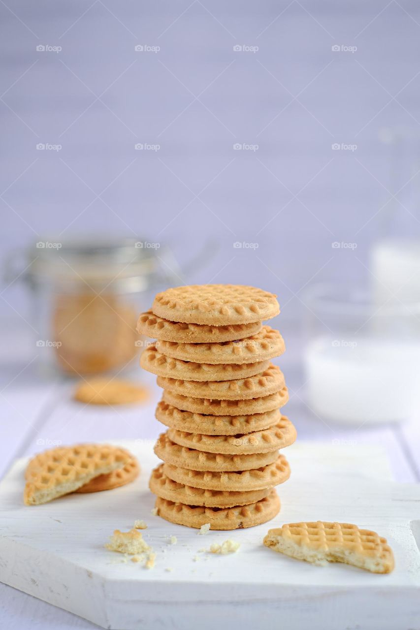 Milk butter cookies stack on wooden cutting board. Traditional dessert, nutrition snack, dessert or breakfast food. Blue and white background. Closeup food.