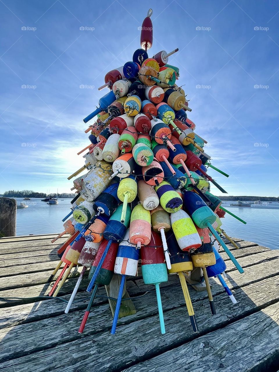 A Christmas Tree made of brightly painted buoys stands at the end of a wharf at Friendship Harbor, Maine.