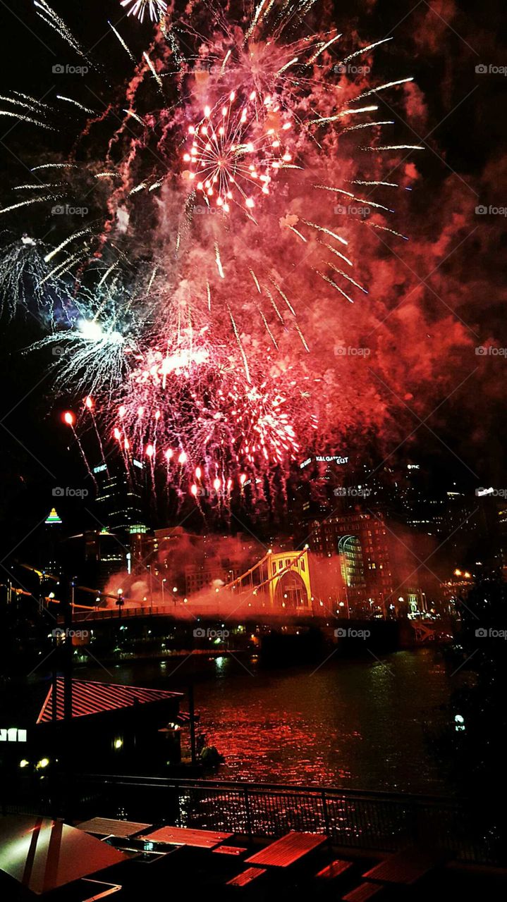 Fireworks display celebrating a holiday party in the city right along the river.