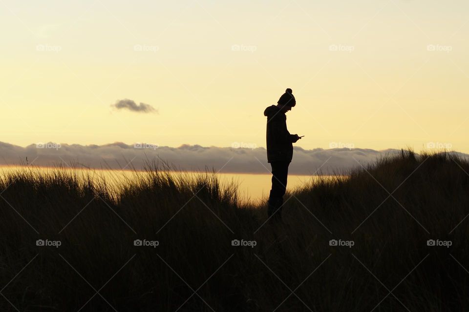 Scrolling through photo’s for Foap  Missions I found this one of my son trying to get a signal on his phone on Holy Island … love his pom pom silhouette ! 