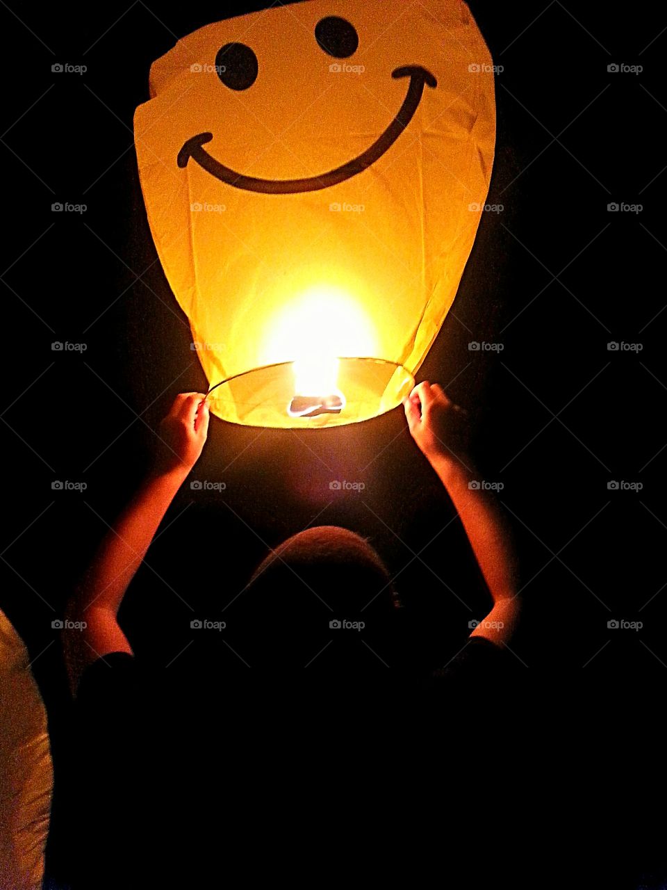 A boy let's go of a lantern.