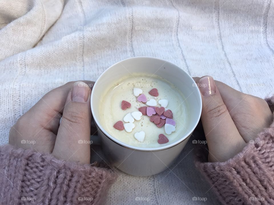 Cup of hot white chocolate in a warm cozy sweater.