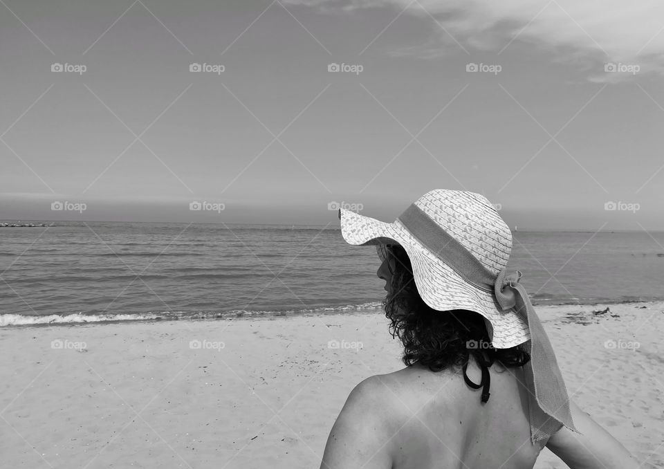 woman whit hat looks at the sea