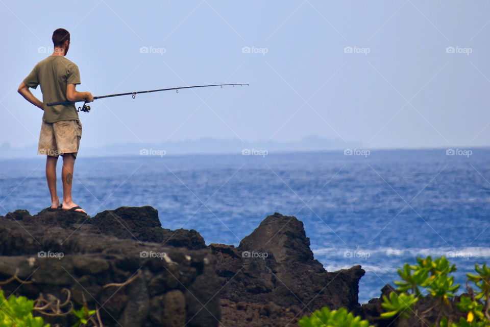 Fishing the ocean from the lava rock sea cliffs on the East side of the Big Island of Hawaii.