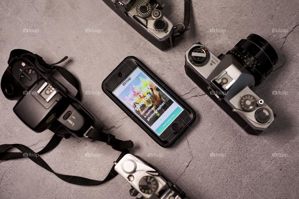 Foap app open on smartphone lined up with 35 mm cameras
