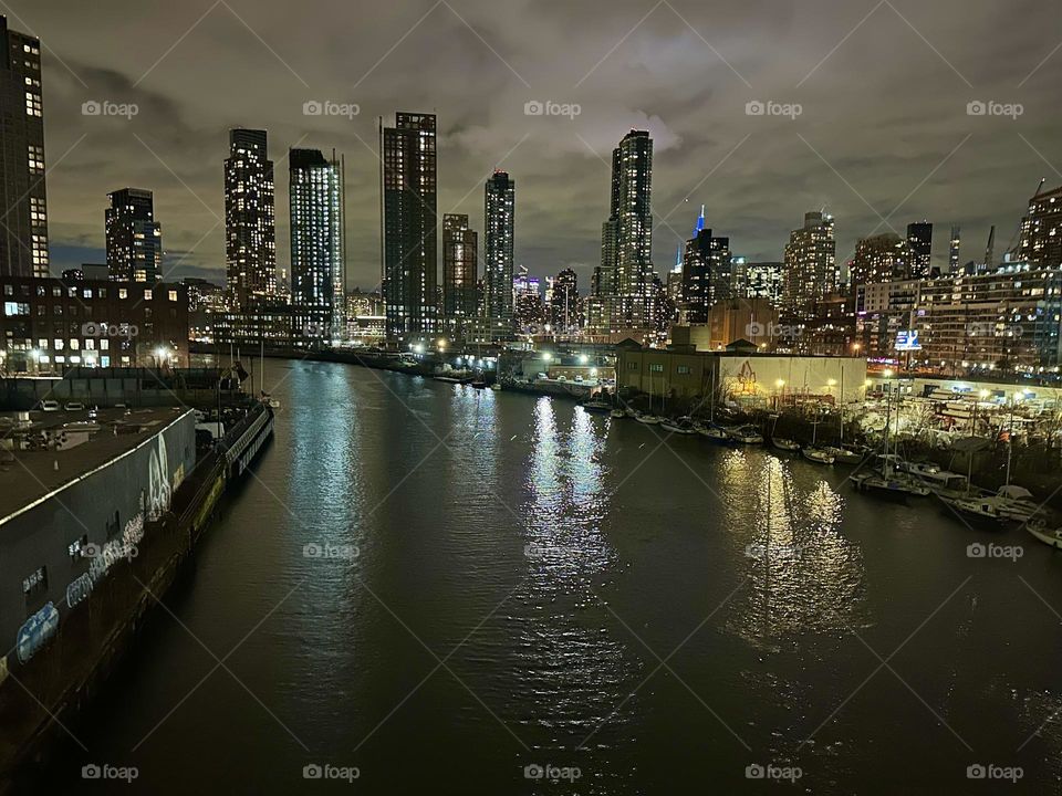 This is “Newtown Creek” at night seen from the “Pulaski Bridge” that connects “Greenpoint”, Bklyn and LIC, Queens presenting an in depth look at the “Big Apple”, NYC. We see “Brooklyn” and LIC as well as “Manhattan”. 2023. Hypnotic Productions