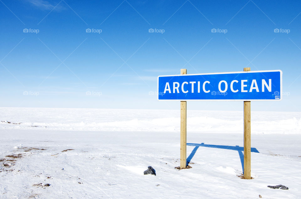 Arctic Ocean sign in Tuktoyaktuk, Northwest Territories, Canada, with frozen ocean in background