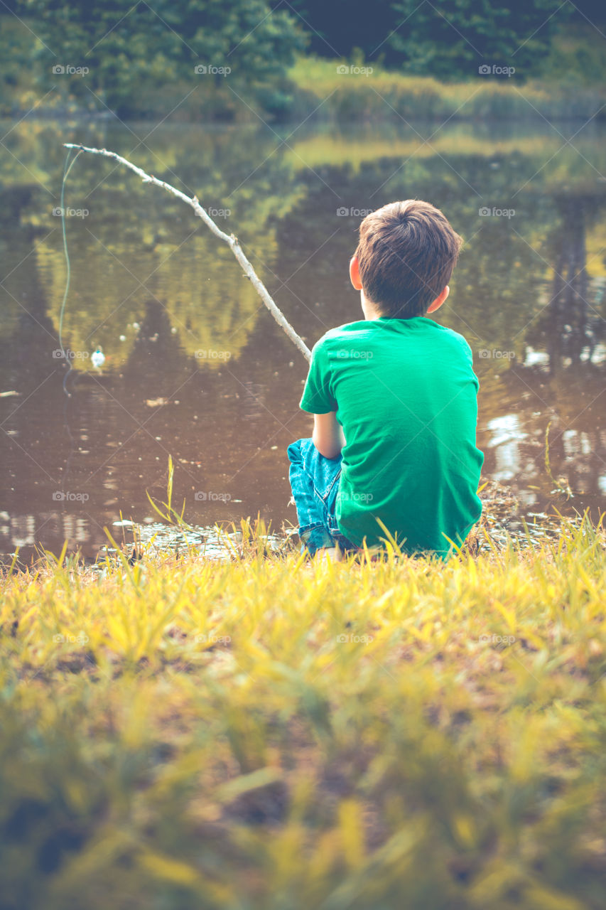 Young Boy Fishing at the Edge of a Pond with a Stick Pole 2