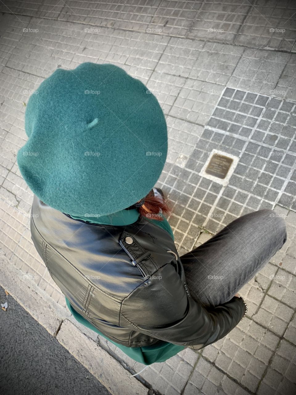 Woman kneeling and viewing a stumble stone in Ancona, Italy
