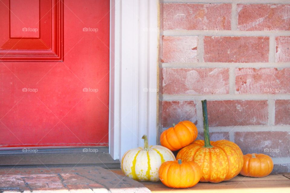 fall pumpkins on front porch by a red door