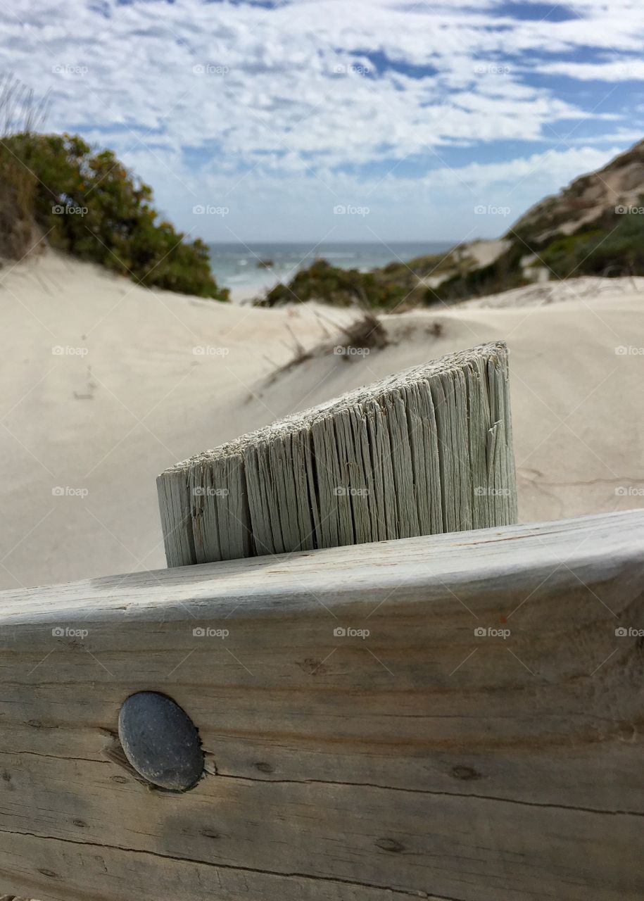 Weathered wood railing foreground on way to ocean 