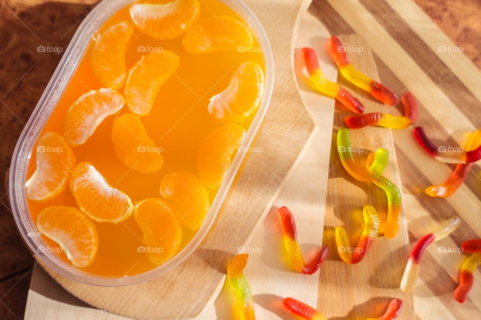 Delicious orange jelly with tangerine slices in a container and jelly worms.