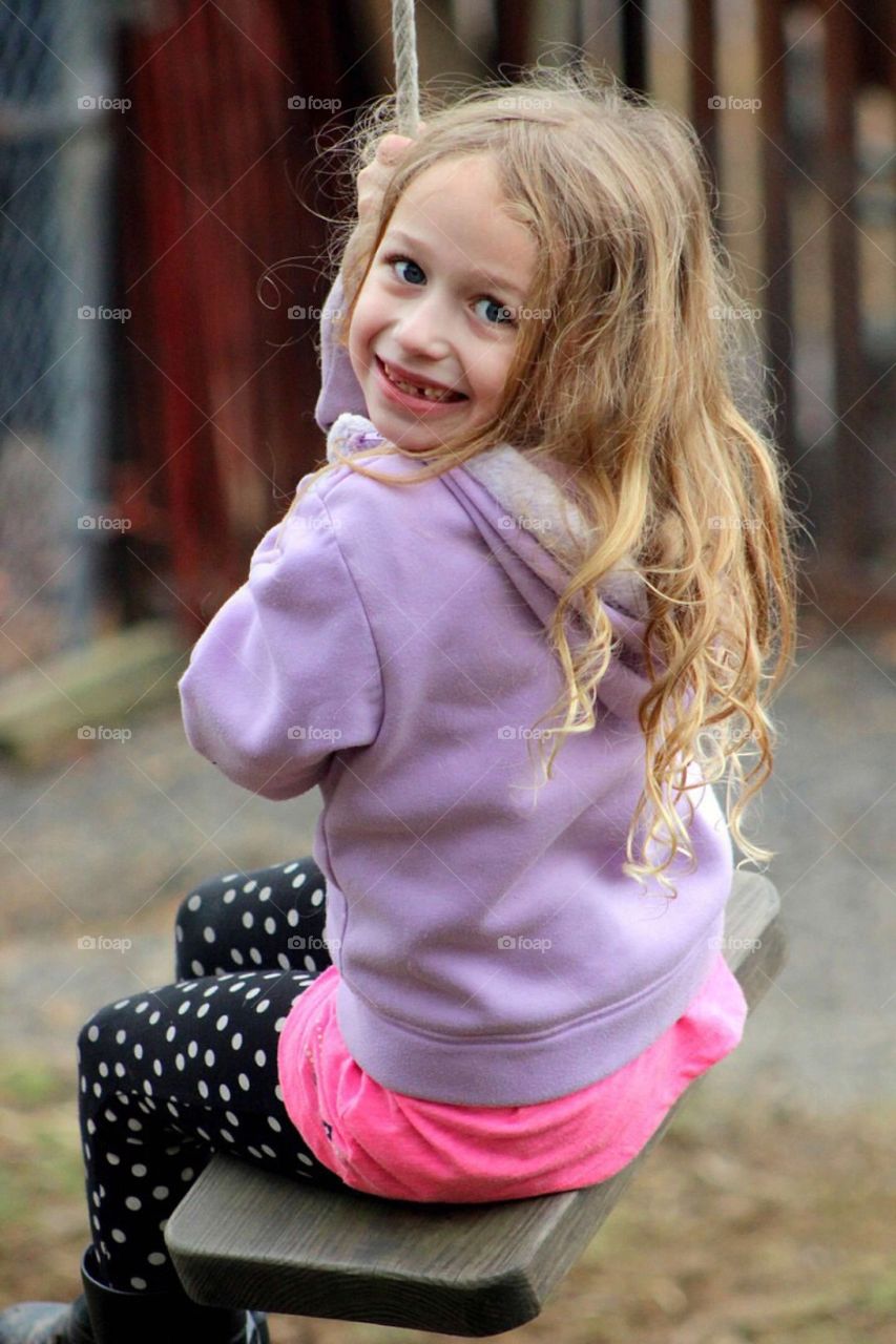 Smiling girl sitting on swing