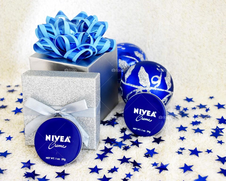 Silver gift box with blue bow and Christmas bulbs and Nivea