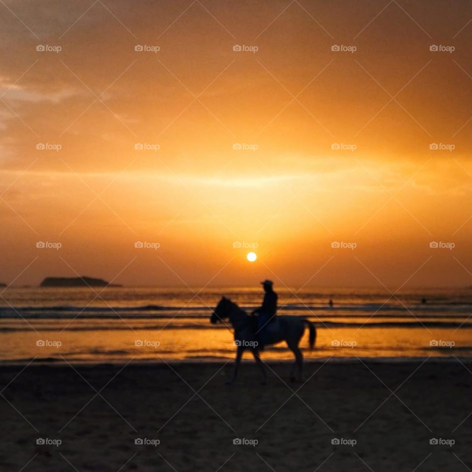 a young man on horseback watching the magic sunset at essaouira city in Morocco.