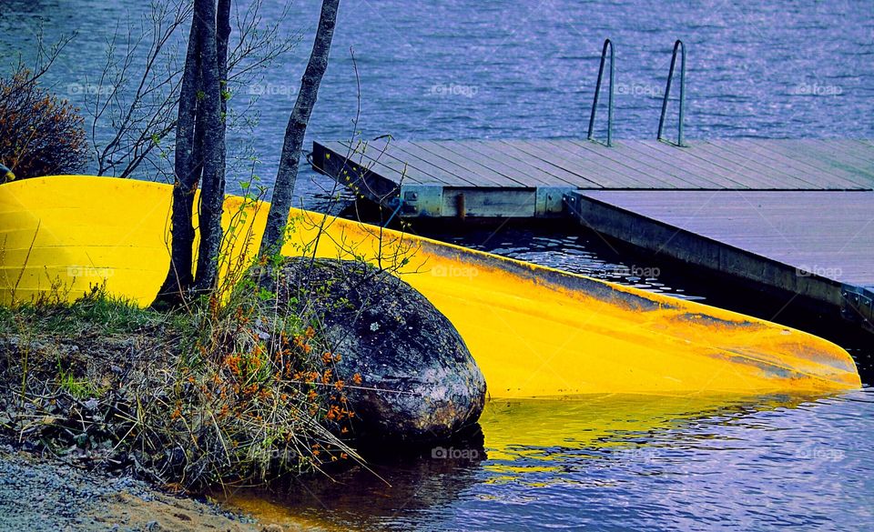 Yellow contrast. Boat laying in the cold blue water