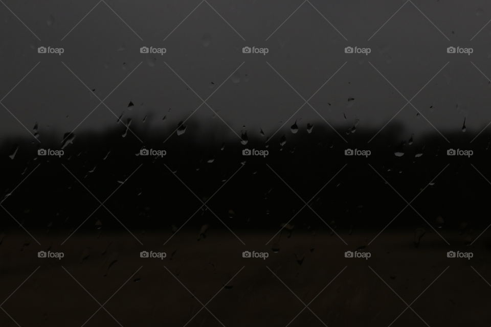 Looking out of the rain covered window. Dark background.