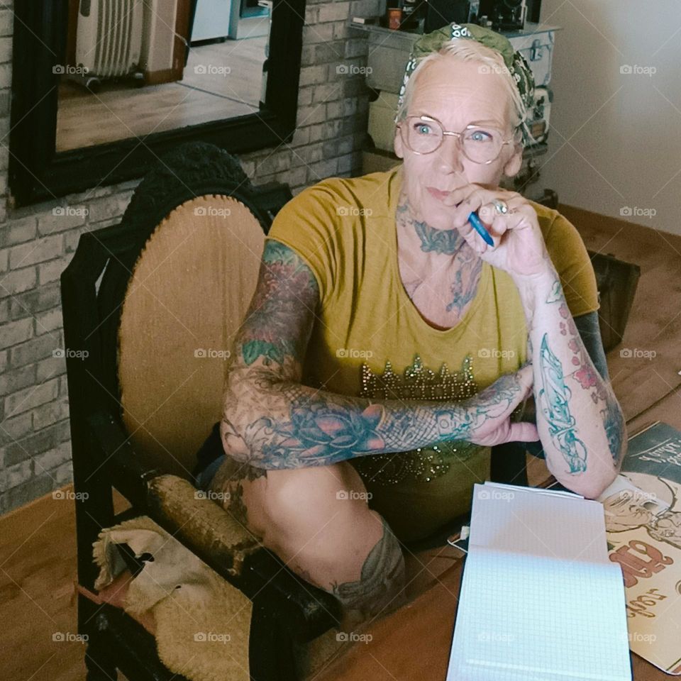 middle aged woman with tattoos sitting at a desk