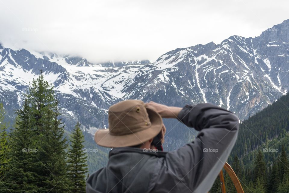 Back view head and shoulder shot male photographer photographing Rocky Mountains