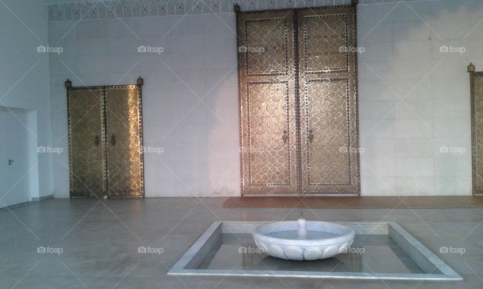 a fountain in front of a large golden door of a mosque