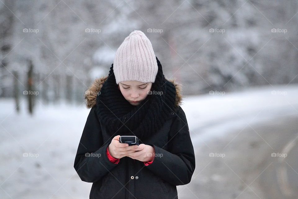 Woman in hat using smartphone at road