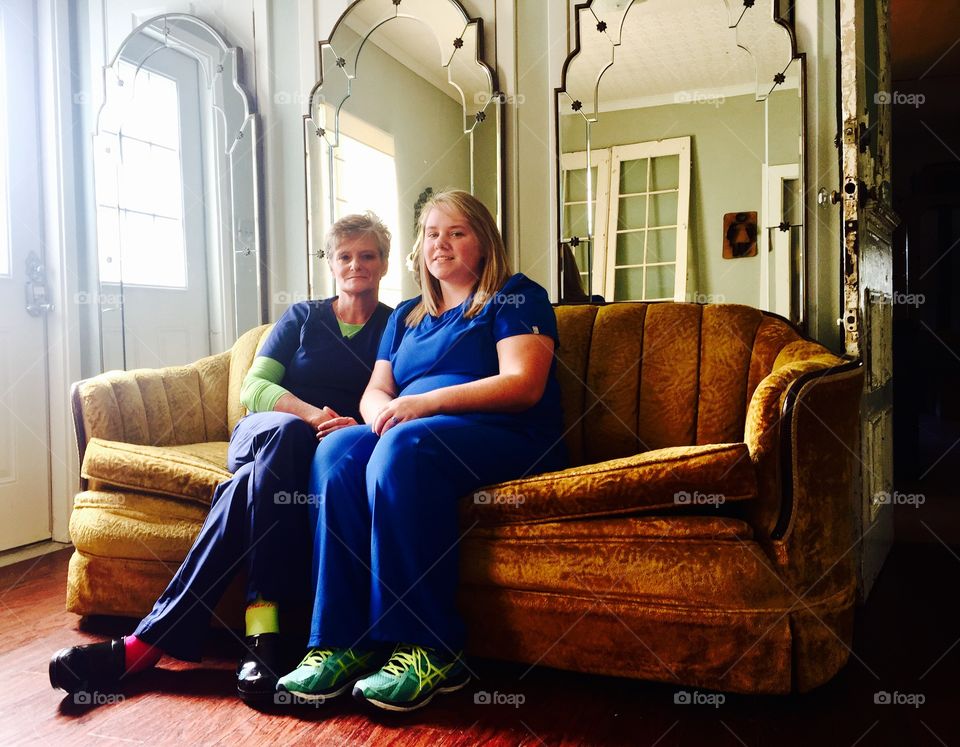 Happy mother and daughter sitting on sofa