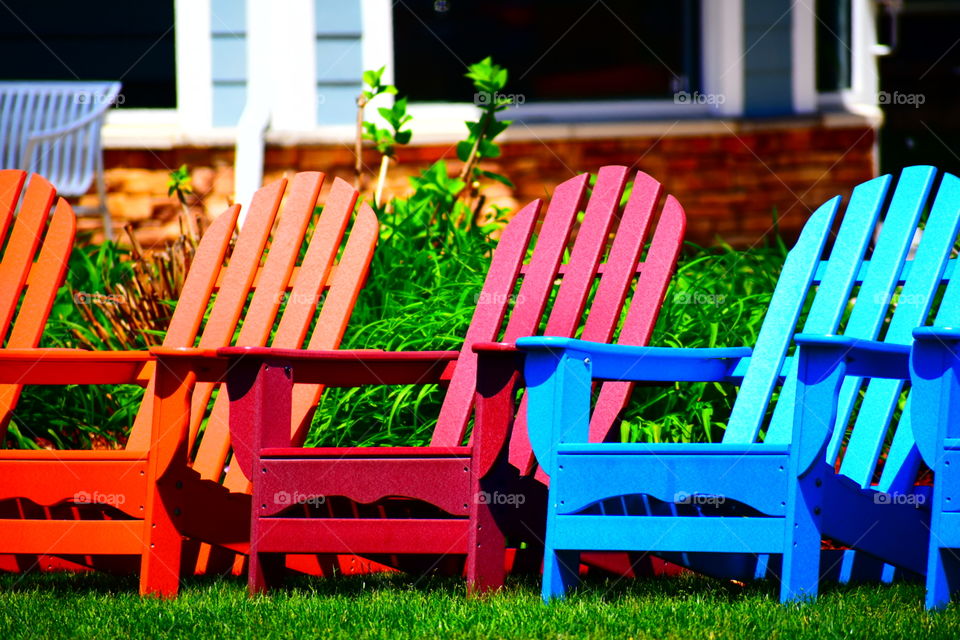 orange, red, and blue lawn chairs sitting on green grass.