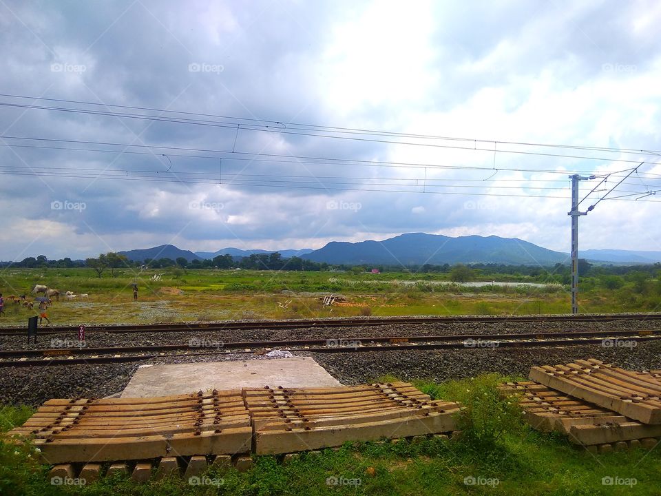 Railway track nearby the green field and hills
