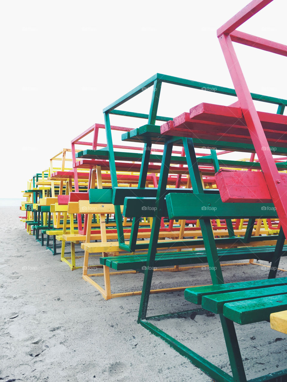 Bright and colourful wooden benches stacked together at a beach.