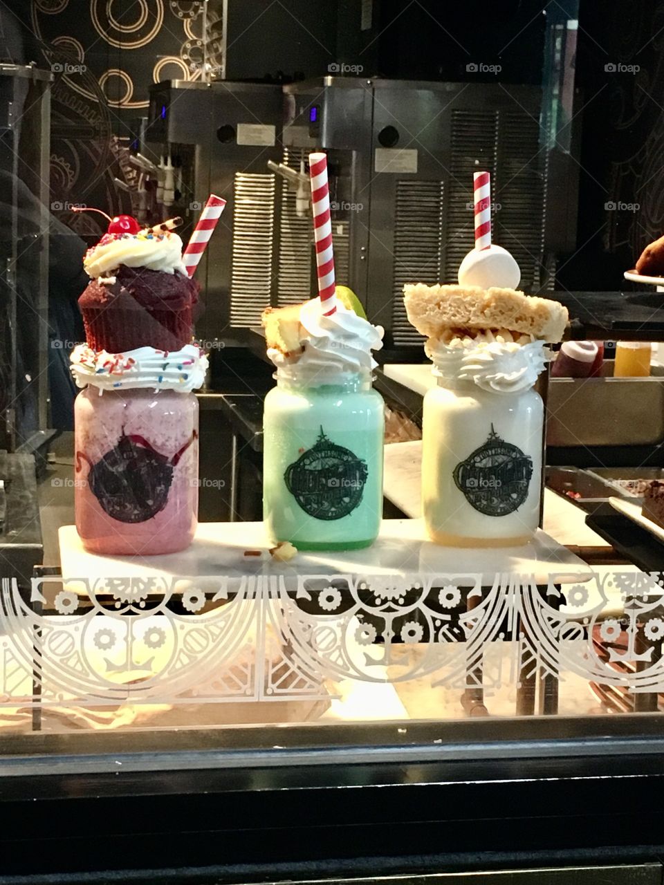 Three incredible looking milkshakes on display in a display case 