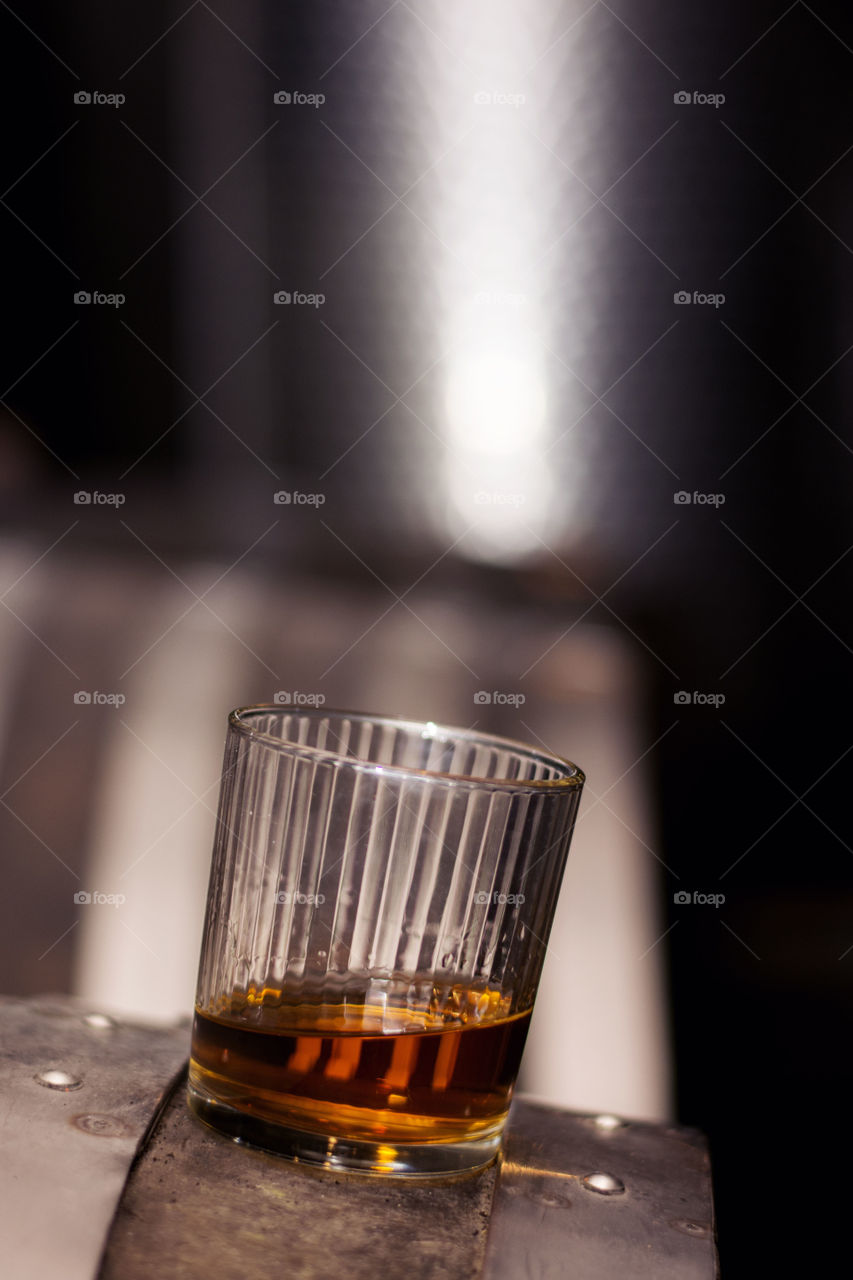 glass of whiskey on top. glass.of whiskey on top of the barrel.in distillery