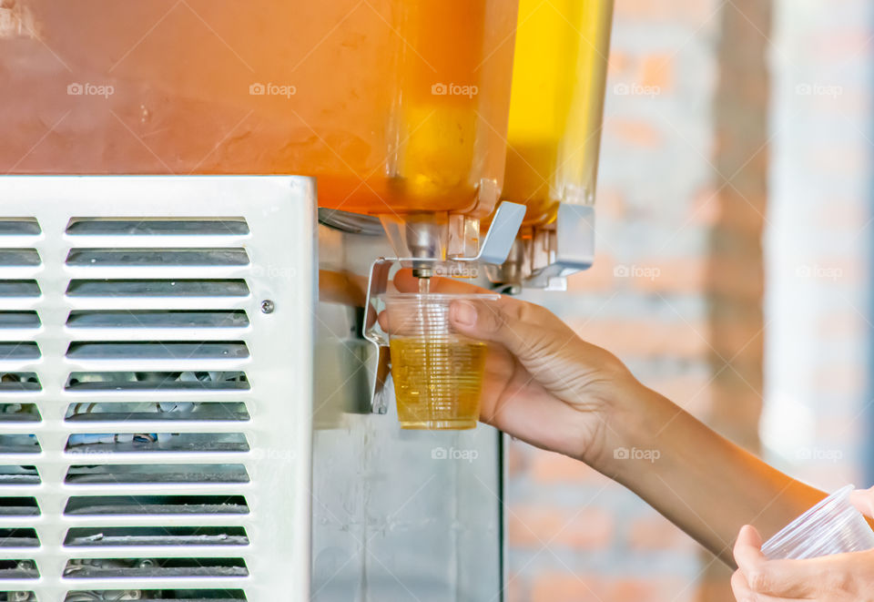 The hand holding the cup plastic flush tea from Juice Dispensor.