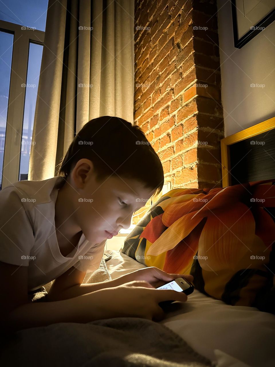 red-haired boy watching a movie in the evening at home on the smartphone 