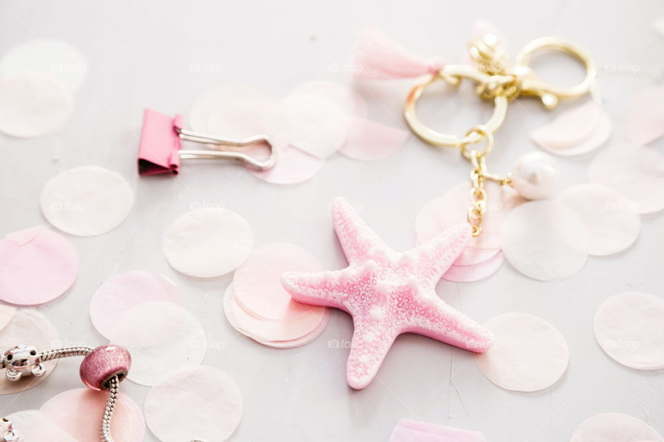 Accessories, pink star lying on gray concrete background with confetti 