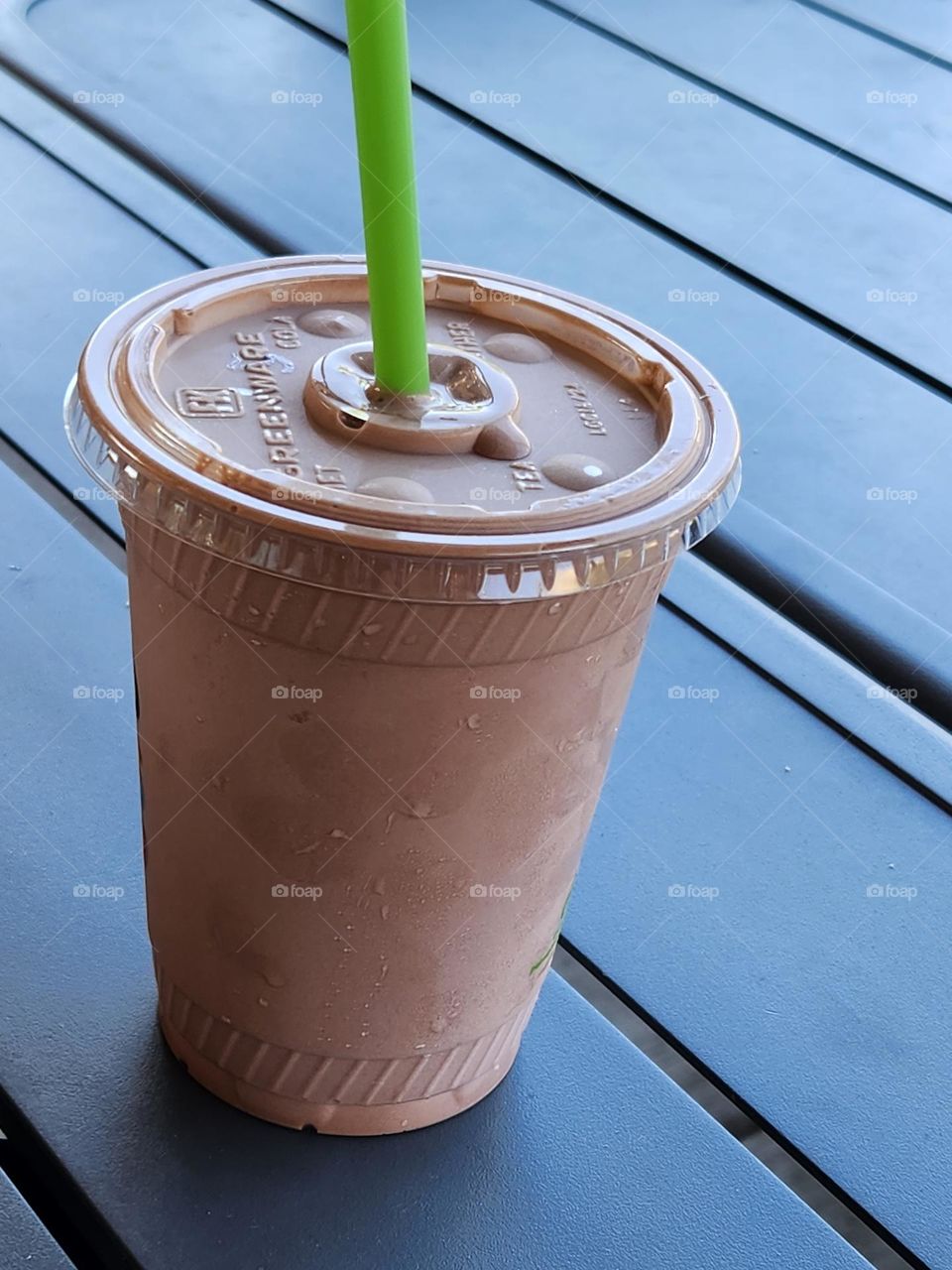 close up of chocolate milkshake with green straw at local restaurant