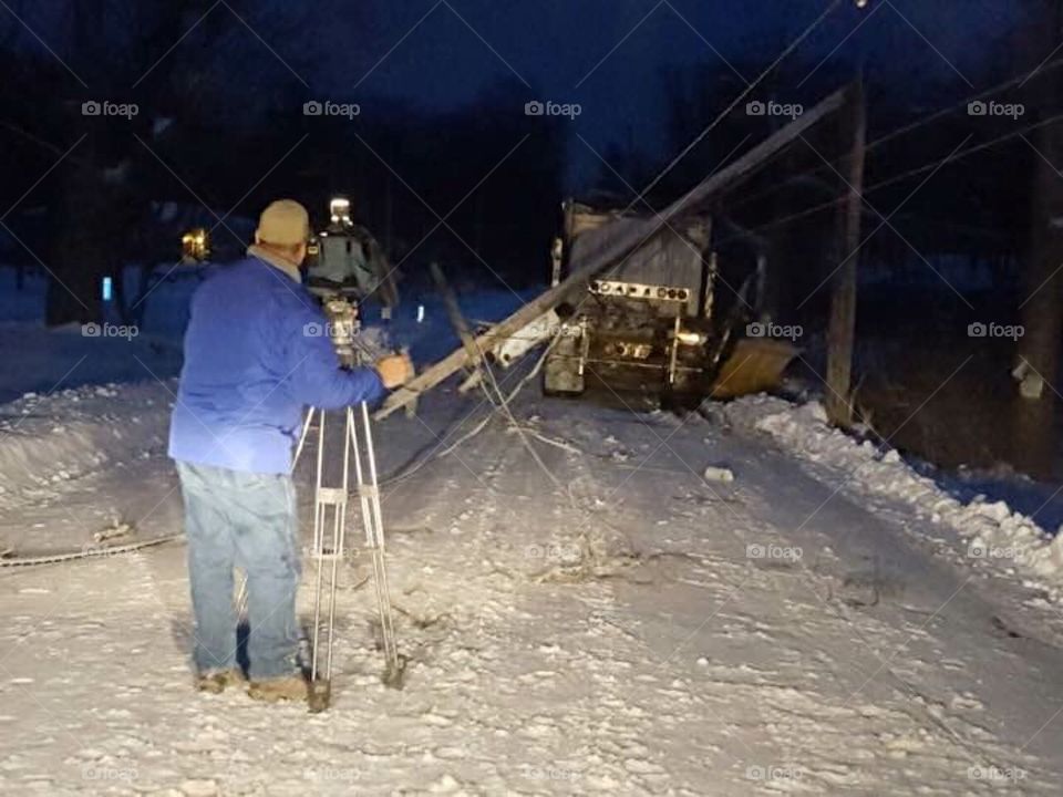 News videographer on the job shooting a downed telephone pole