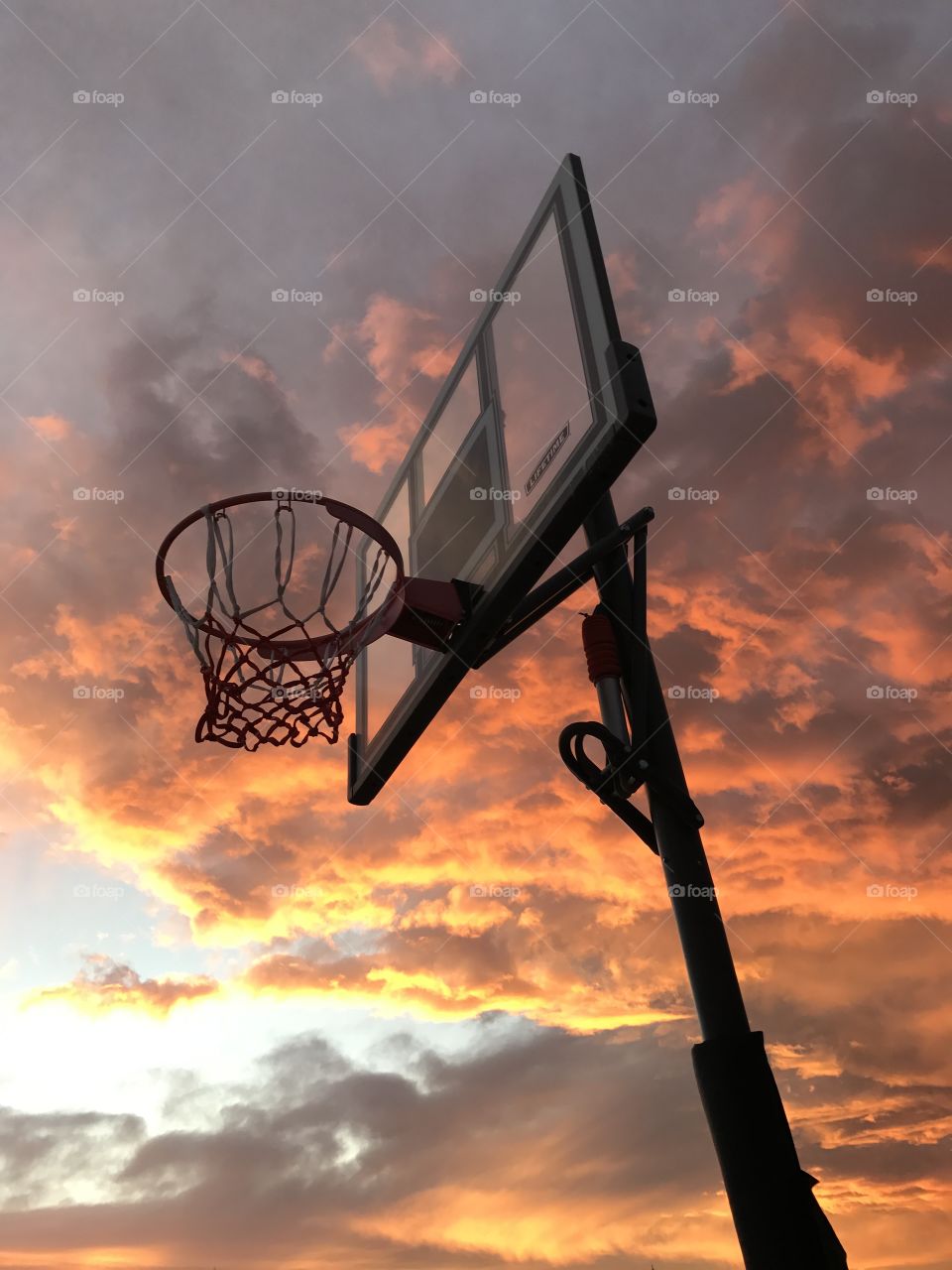 Basketball hoop backlit by sunset