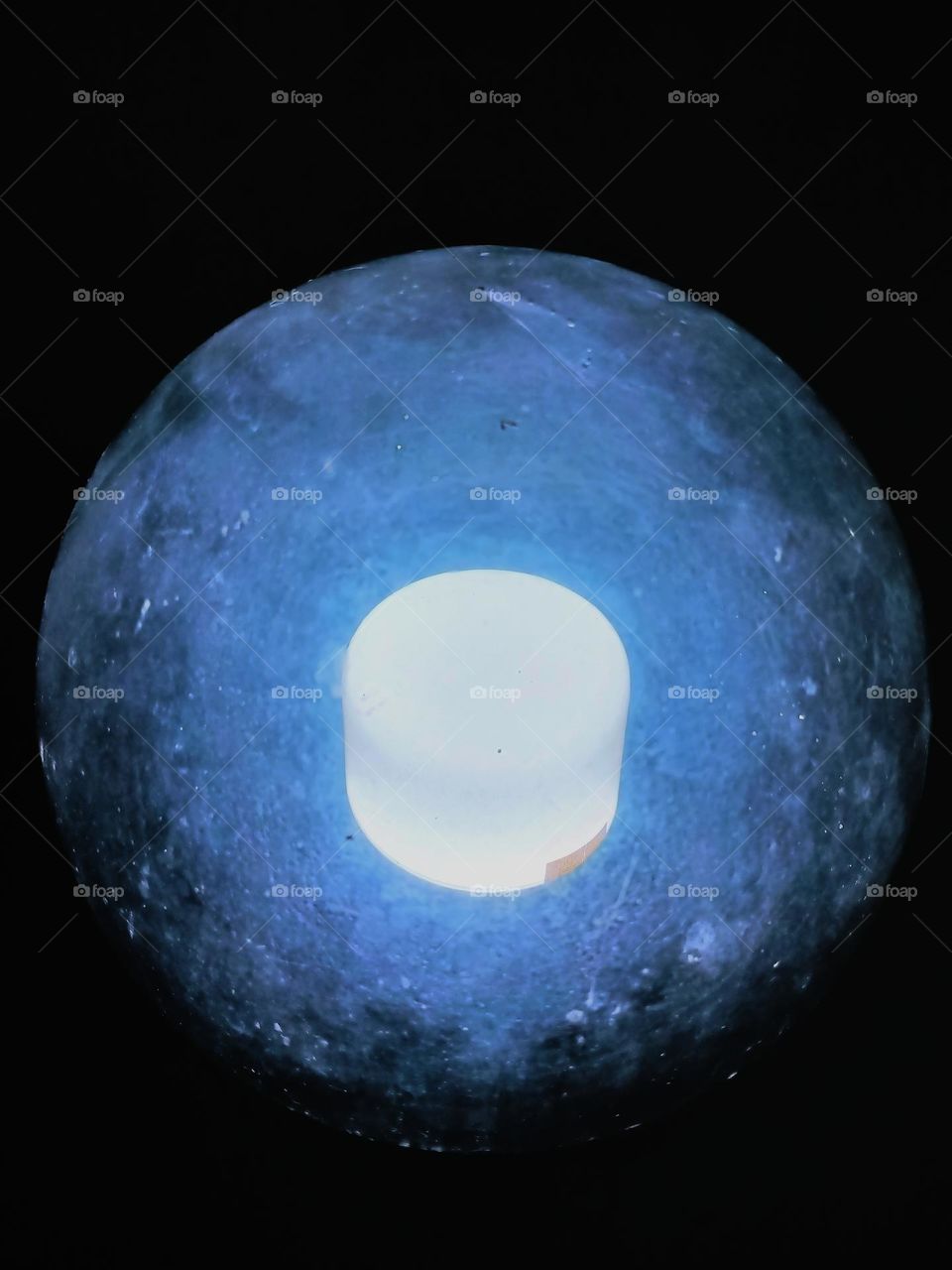 Close-up of round and transparent glass lamp on black background.