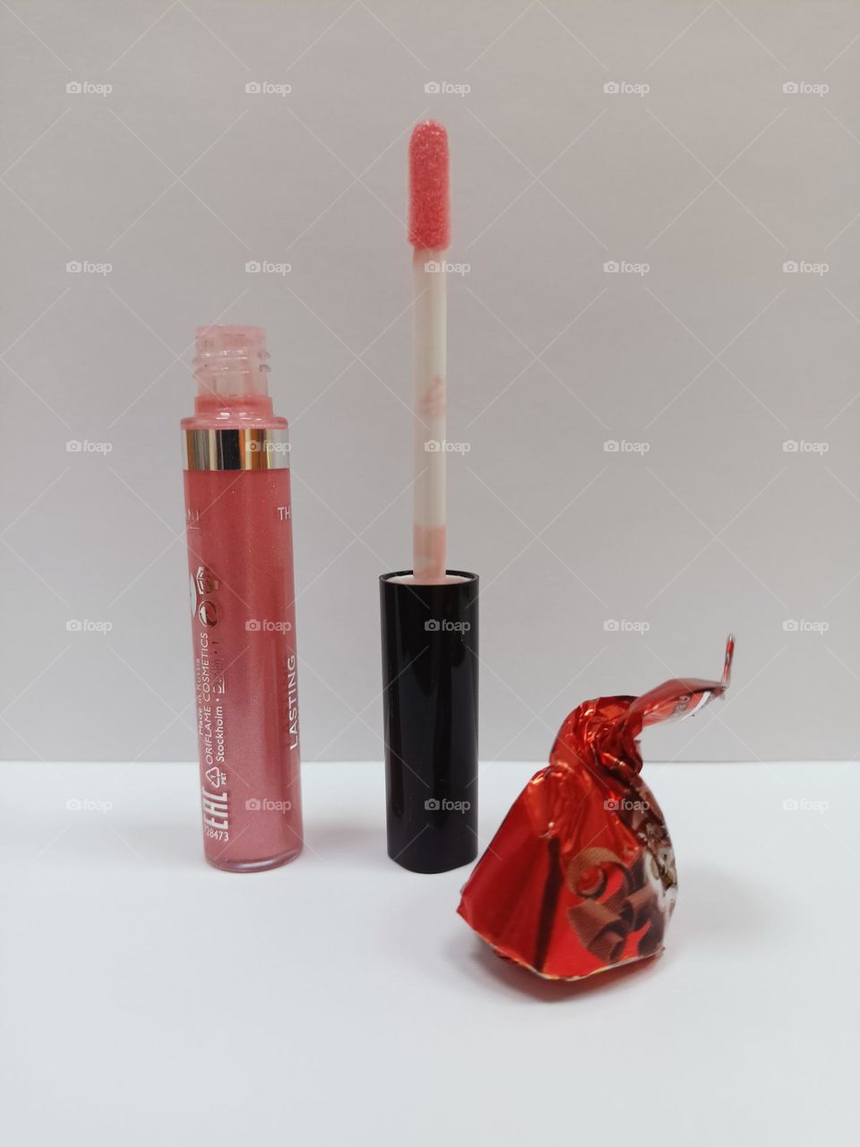 lip gloss, liquid lipstick, cosmetics, white background, chocolate candy in a wrapper