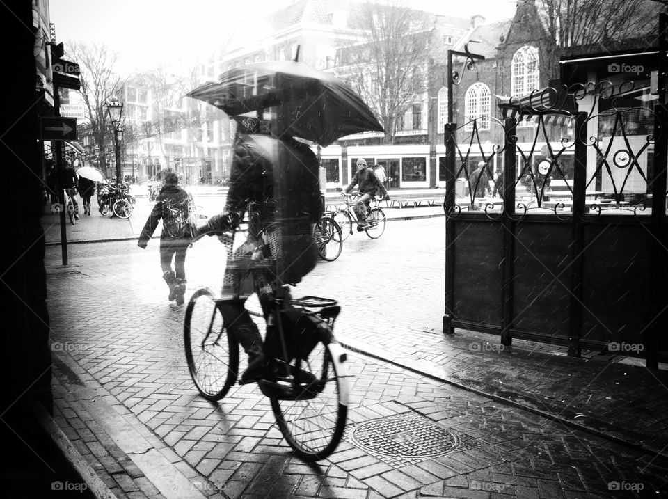 A man riding his bike through Amsterdam in the snow.