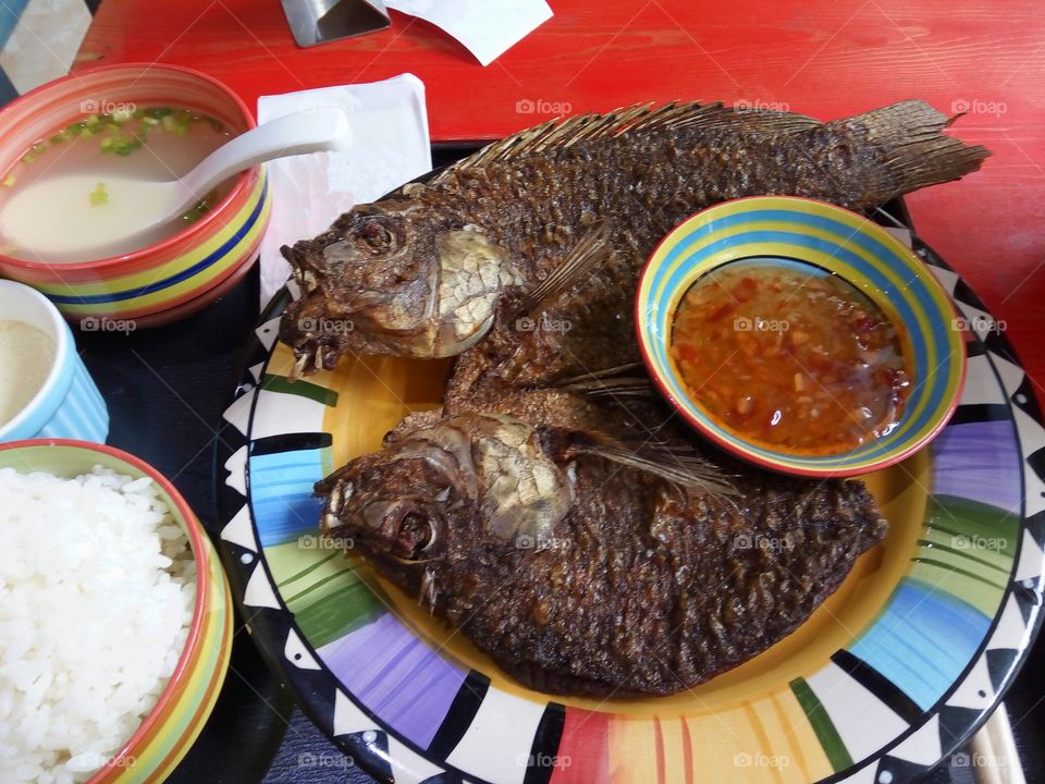 Fried fish in a spicy sauce on metallic dish.