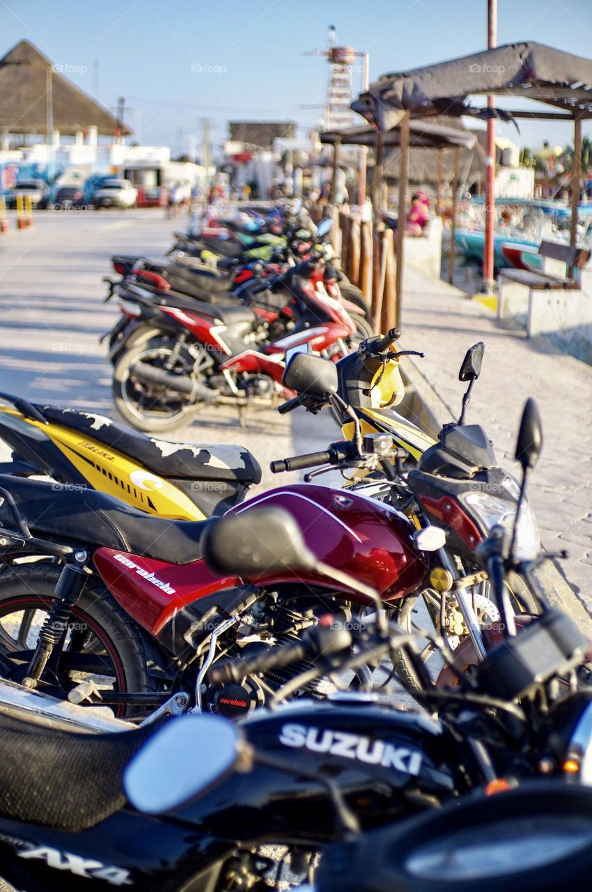 A row of motorcycles lined up at the peer wait for commuters to return from their work day on Holbox Island.