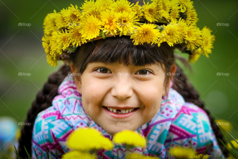 Cute smiling girl in dandelions wreath