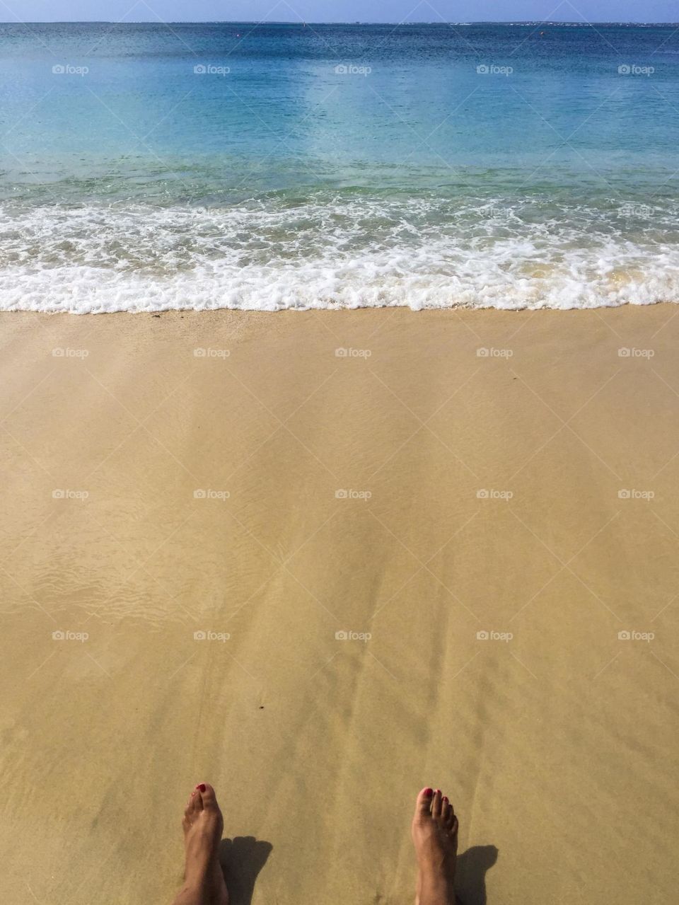 Woman relaxing on the beach, toes in the sand, woman’s feet relaxing on the beach, point of view from the beach, seaside vacations, relaxing by the water, woman’s feet in the sand on vacation 