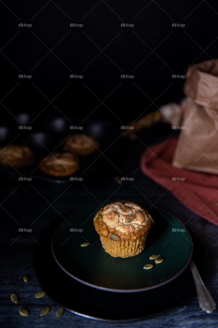 Dark and moody image of a baked pumpkin cheesecake muffin 